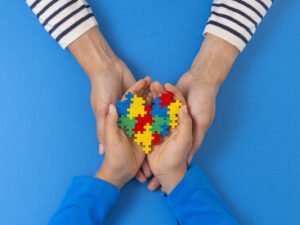 teach and student hands holding autism puzzle