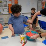 Autism student and teacher mixing food