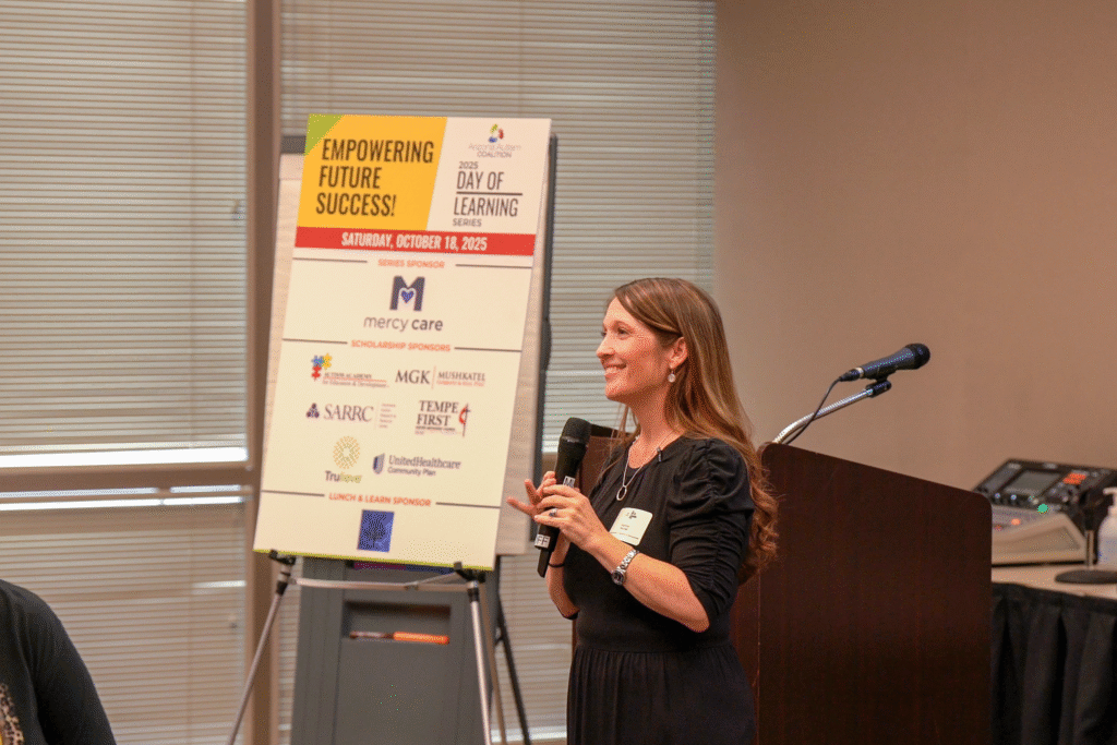 Woman with long brown hair holds microphone speaking to a room of professionals