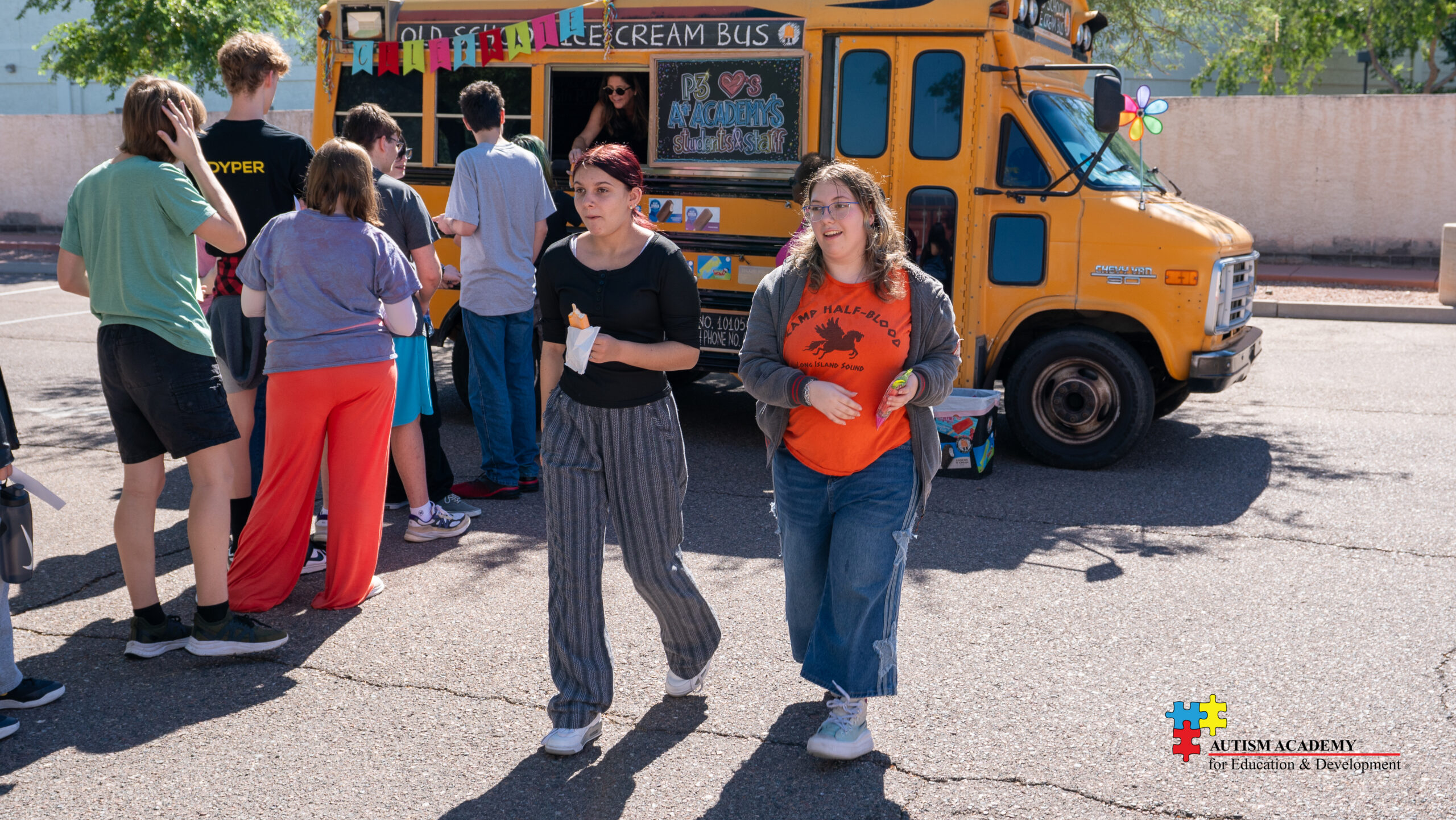 students eat ice cream outside of an old fashioned school bus that sells it.